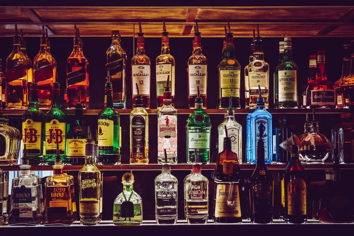 Barra de bar iluminada con estantes llenos de botellas de licores