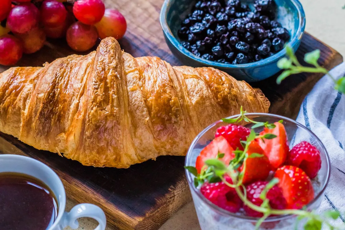 Croissant con taza de café y frutas en un desayuno de cafetería