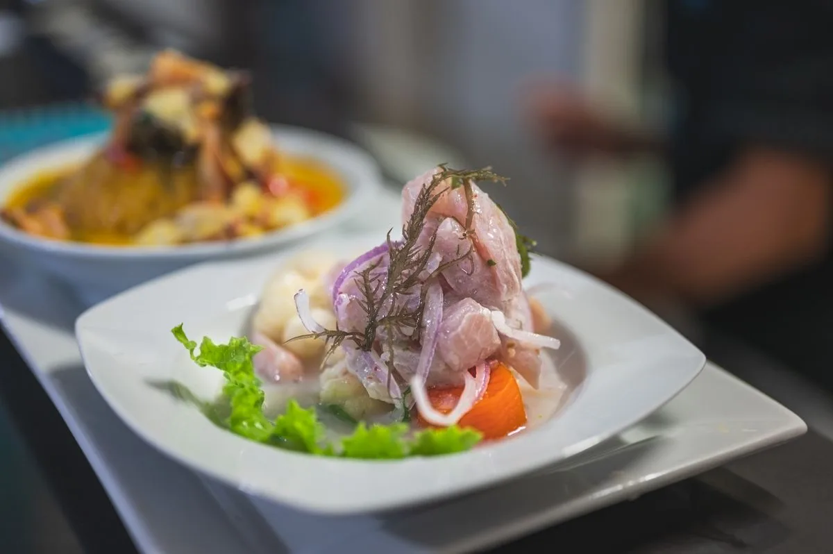 Ceviche clásico con cebolla roja, camote y yuyo servido en plato blanco