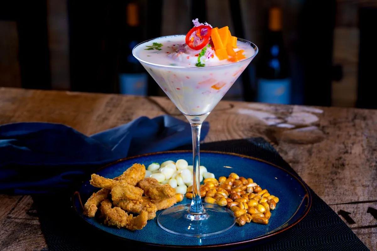 Leche de tigre en copa acompañada de canchita y chicharrón de pescado
