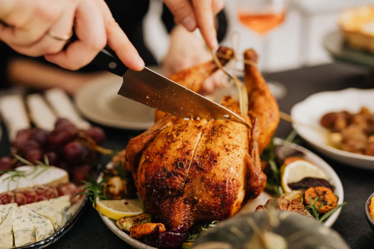 Pollo entero trinchado en una mesa familiar con guarniciones
